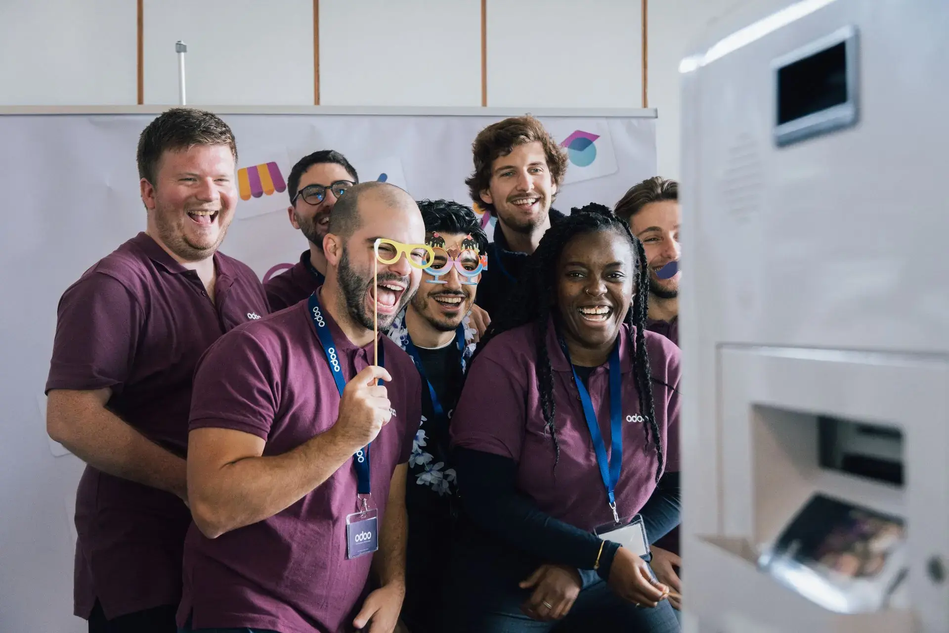 group of Odoo employees around a camera at Odoo Experience 2024